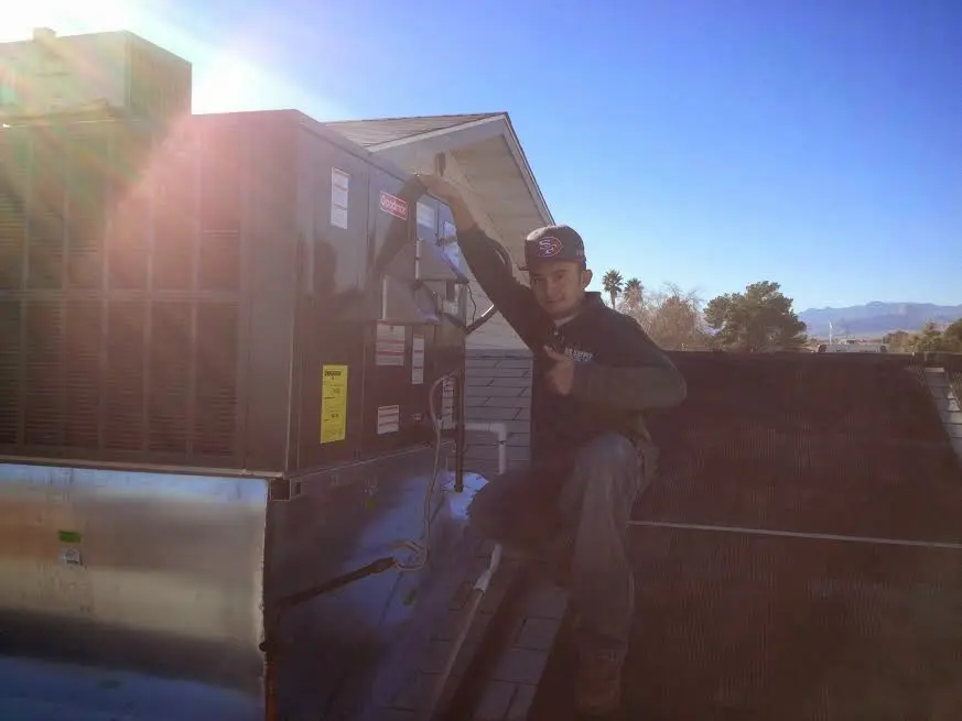HVAC technician performing Air Duct Repair on a rooftop unit in Belding